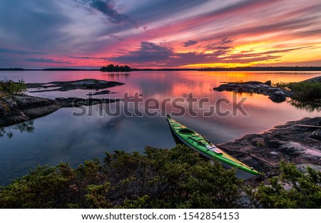 A kayak stopped on the shore of Eagle Lake at sunset on a calm evening in Northwest Ontario, Canada  Royalty-Free Stock Photo #1542854153