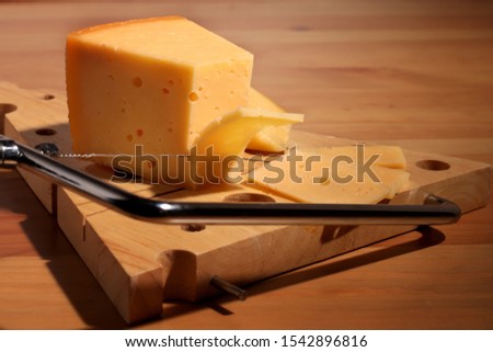 Piece of cheese on a wooden board
Cheese knife