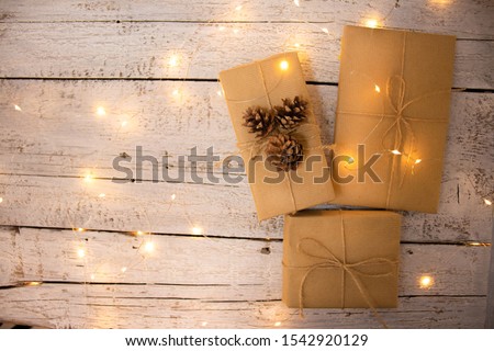 Box in craft packaging, decorated with cones and a garland with warm colors on a white background. DIY packaging