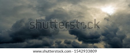 dramatic mystical sky with gray heavy clouds and faint back sunlight and lumen. artistic panoramic picture for the original background, layout or decoration