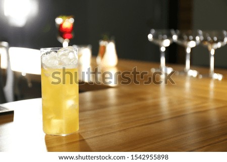 Glass of delicious cocktail with vodka on wooden counter in bar. Space for text