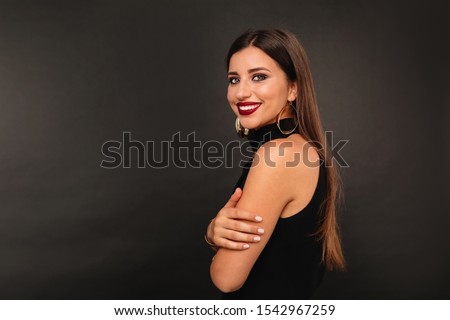 Beauty fashion portrait attractive woman with red lips posing to camera. Smiling young woman on dark wall background.