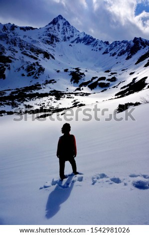 Dramatic picture of a woman standing under snowy mountain - High Tatras, Slovakia