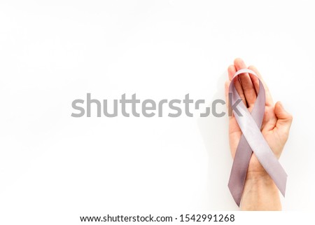 Disease control concept. White ribbon in hands on white background top view copy space