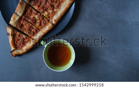 Turkish pizza pide with minced meat and cup of tea( coffee) on a dark background.