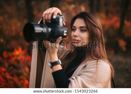 beautiful woman photographer takes pictures in nature in autumn, the photographer in action