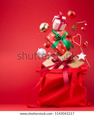 Christmas shopping. Magic fly or falling concept. Red cotton bag with gift boxes, candy, cinnamon and other New Year decorations.