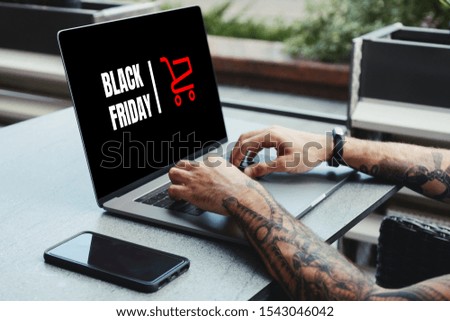 Black Friday banner in a laptop computer while man shopping online in coffee shop.