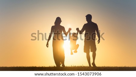 Happy family silhouette on sunset background. Father, mother, baby son run. Child jumping and playing with parents. 
