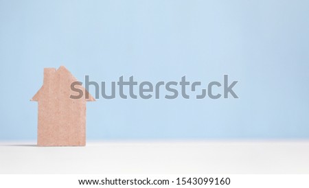 Abstract cardboard house on a blue background. Concept with place for an inscription. Horizontally with a large place for text. Copy space.