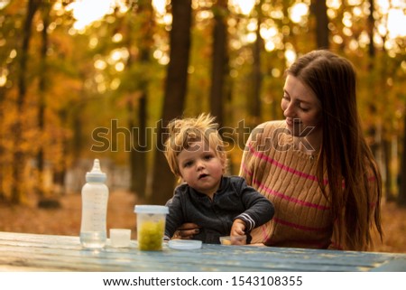 Beautiful mom feeds the child in the autumn park with fresh fruits. Healthy food. Lifestyle.