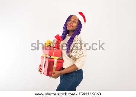 A dark-skinned happy girl holds a lot of red gifts in her hands. The concept of new Year, Christmas gifts, giving, Christmas shopping. Template for your advertising.