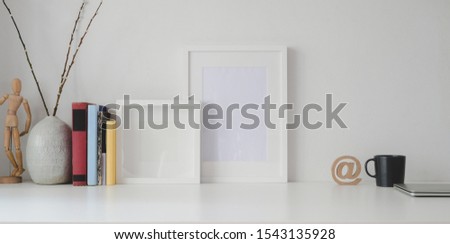 Minimal workspace with mock up frame and office supplies on white wooden table and white wall background 
