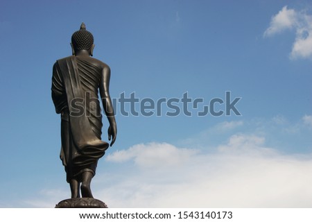 Back side of a Buddha statue standing with blue sky background at Wat Saman Rattanaram Temple in Chachoengsao Province of Thailand.