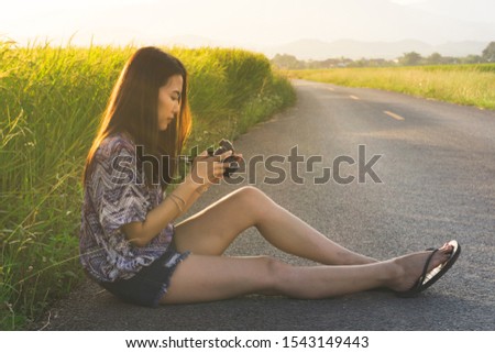 portrait of woman hold camera,sitting and ckecking photos with beautiful landscape views on background with copy space, vacation, travel and lifestyle concept picture.