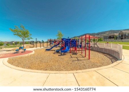 Sunny day at a park with focus on colorful playround against Mount Timpanogos