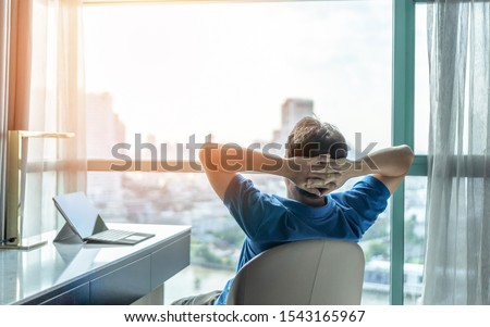 Life-work balance and city living lifestyle concept of business man relaxing, take it easy in office or hotel room resting with thoughtful mind thinking of life quality looking forward to cityscape  Royalty-Free Stock Photo #1543165967