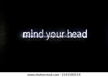 A closeup shot of an led sign spelling mind your own head with a black background
