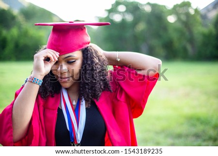 Candid Portrait of a beautiful multiethnic woman putting on her graduation cap and gown. Selective focus on her beautiful face