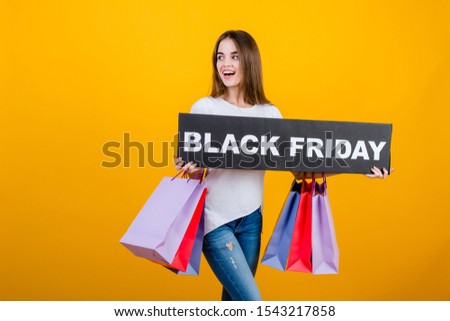beautiful brunette woman with colorful shopping bags and copyspace text black friday sign isolated over yellow