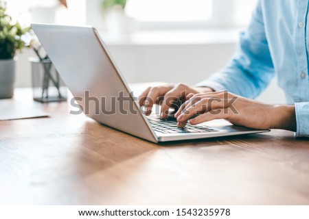 Hands of young contemporary office manager over laptop keypad during work over new business project by table Royalty-Free Stock Photo #1543235978