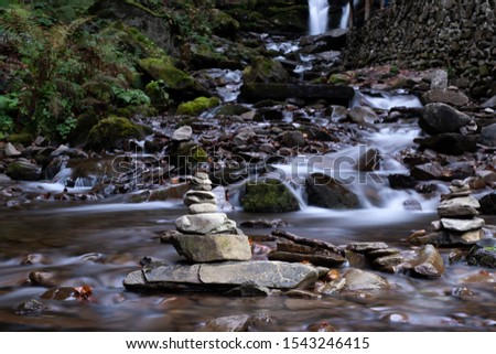 Long exposure photo. Flowing water. Wallpapers with amazing natural stones and waterfall at background. Soft focus due to slow shutter at windy area