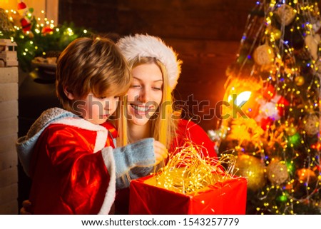 Mother and son in Santa costume opening Christmas amazing gifts. Christmas eve. Holiday. Indoor. Home. Family winter holidays and people concept