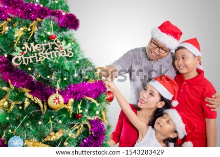 Picture of Asian family looks happy while putting ornaments on a Christmas tree