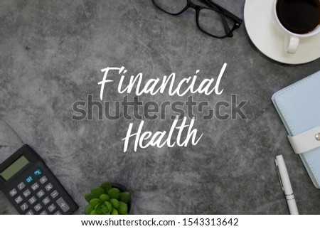 Top view of calculator,plant,pen,notebook, a cup of coffee, glasses on grey grunge floor written with Financial Health.