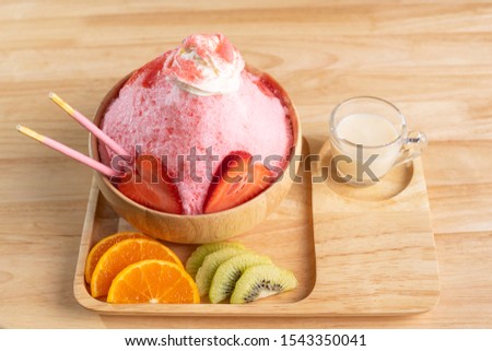 Bingsu or shaved ice in a wooden cup decorated with strawberries, oranges and kiwi