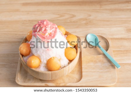Bingsu or shaved ice in a wooden cup decorated with cantaloupe.