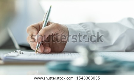 Medical doctor writing on patient personal health care record discharge form, or prescription paperwork in hospital office, clinic center for healthcare and life insurance concept