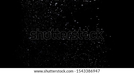 Blurry images of soda water bubbles splashing and floating up to top of water surface which little and big circle texture shaped up by gas power in carbonate drink make refreshing on black background Royalty-Free Stock Photo #1543386947
