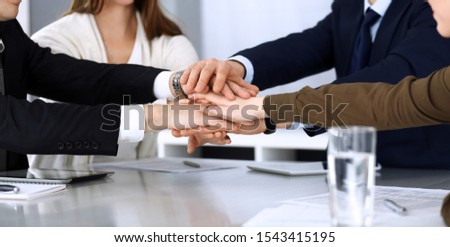 Business people group showing teamwork and joining hands or giving five after signing contract in modern office. Unknown businessman and woman with colleagues or lawyers making circle with their hands