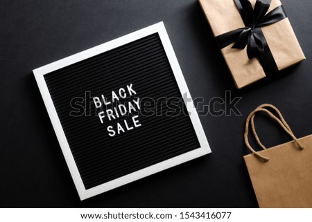Black Friday sale concept. Letter board with sign "Black Friday sale",shopping bag and gift box over black background. Flat lay, top view, overhead.