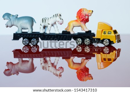 A large yellow truck carries rare African animals: zebra, lion and hippo. Cargo transportation. Delivery of non-standard oversized cargo. Toys
