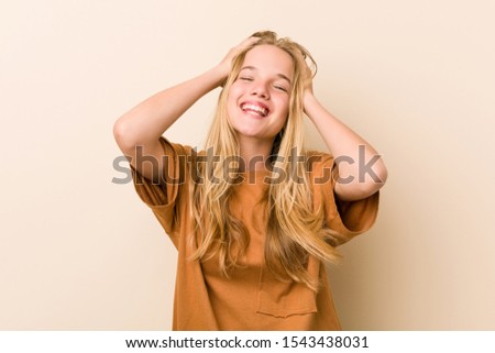Cute and natural teenager woman laughs joyfully keeping hands on head. Happiness concept.