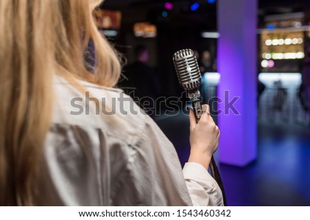 Girl holds vintage microphone in karaoke bar