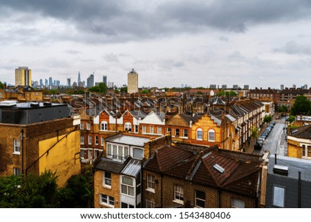 London, UK. Aerial view of residential district with modern skyscrapers at the background in London, UK. Heavy clouds over the city