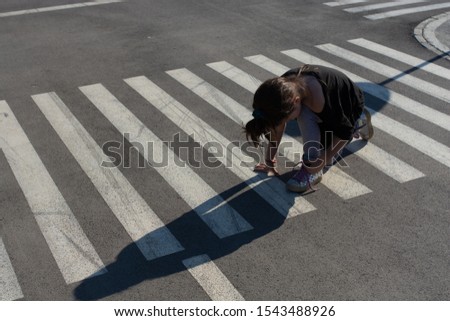 Little girl in low position on cross road sign 
 