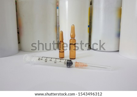 Medical syringe and ampules on drugstore bottles background in self drug intake buying concept