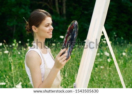 young woman paints on canvas model outdoors paints