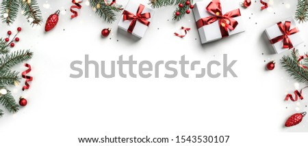 Creative frame made of Christmas fir branches, gift boxes, red decoration, sparkles and confetti on white background. Xmas and New Year holiday, bokeh, light. Flat lay, top view