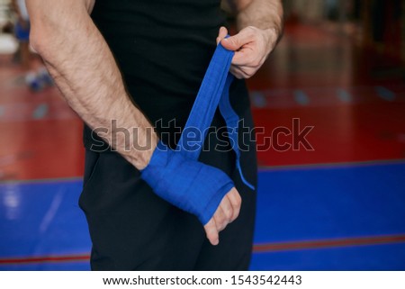 young male athlete wrapping his hand with bandage, close up cropped photo.guy has problems with his arms after training,