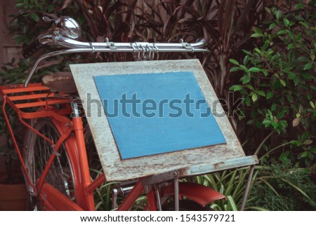 Mock up blank board advertising billboard for wood frame on old bicycle at front restaurant cafe garden tree background, display your product insert  text. retro vintage decoration style