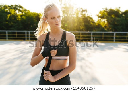 Image of caucasian fitness woman in sportswear training with boxing hand wraps outdoors