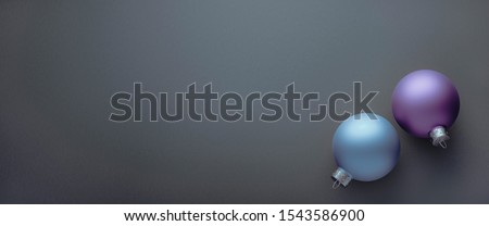 Exciting Two matte blue Christmas balls lying on grey studio background. Template for business greeting card or design. With Copy space.