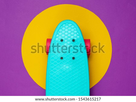 Cruiser board on purple background with yellow circle in the middle. Summer fun. Studio fashion shot. Top view.