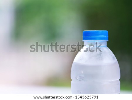 Drinking water bottle closeup in green nature blur background with copy space