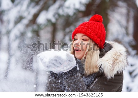 Beautiful young woman blowing snowflakes 